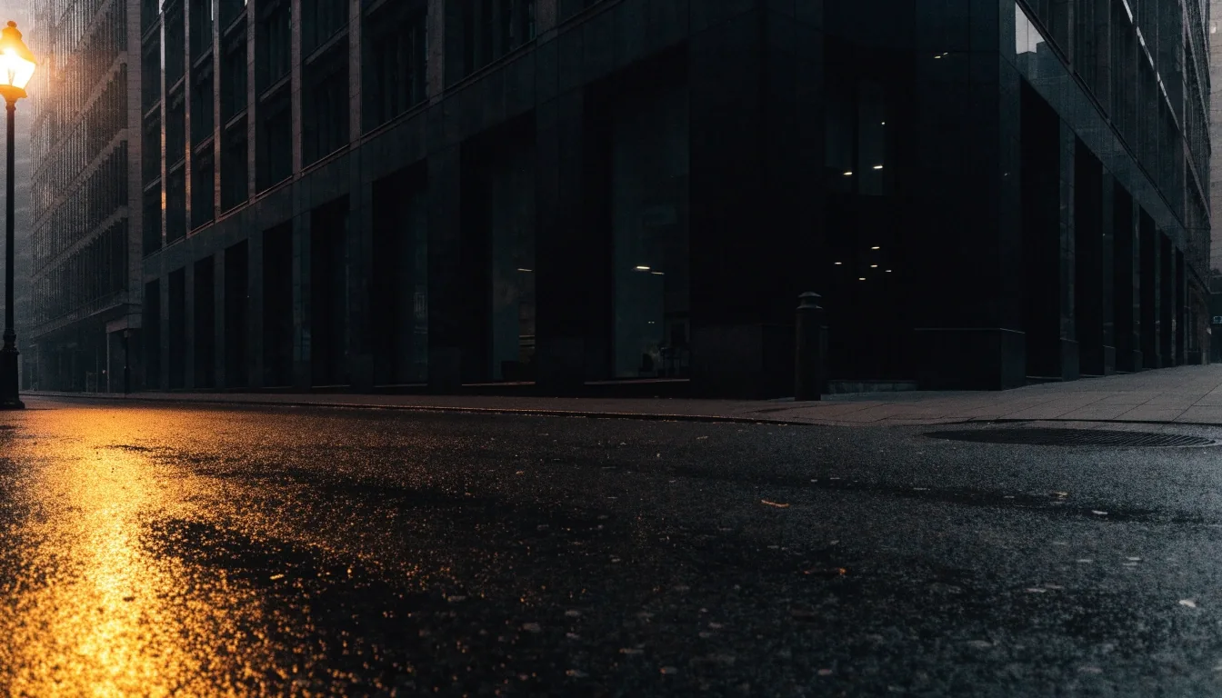 Calle de la City de Londres antes del amanecer, pavimento mojado y luz ámbar en el borde del encuadre