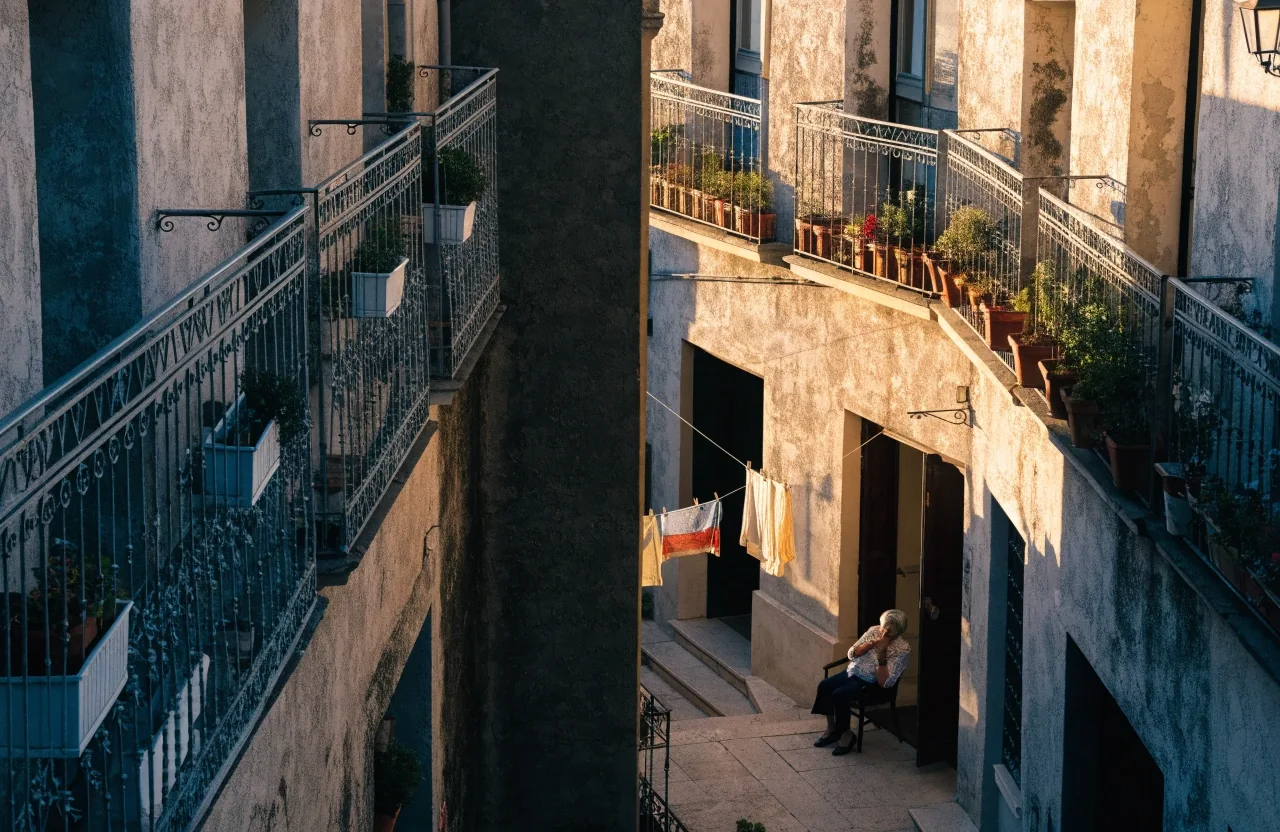 Vecinos reunidos al atardecer en una calle residencial, vistos desde el otro lado de la vía