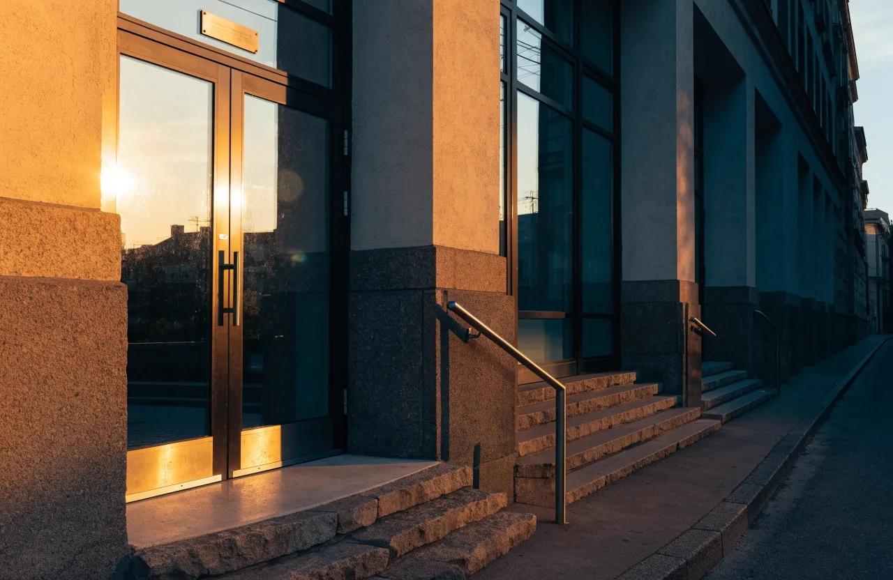 Puerta de acceso a una oficina pública vista desde la acera, al atardecer